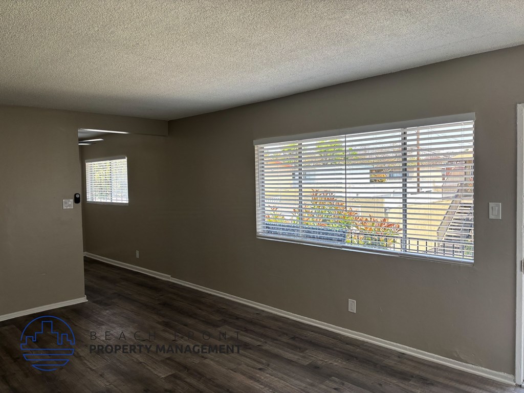 A room with a window showing a view of a building and trees.